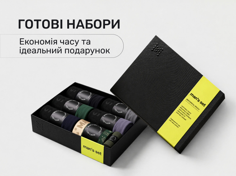 Подарунковий бокс чоловічої анатомічної білизни Man's SET у відкритій чорній рельєфній коробці з фірмовою яскраво-жовтою стрічкою, всередині якої охайно складені рулонами різнокольорові труси-боксери, на білому фоні з рекламним написом Готові набори економія часу та ідеальний подарунок.