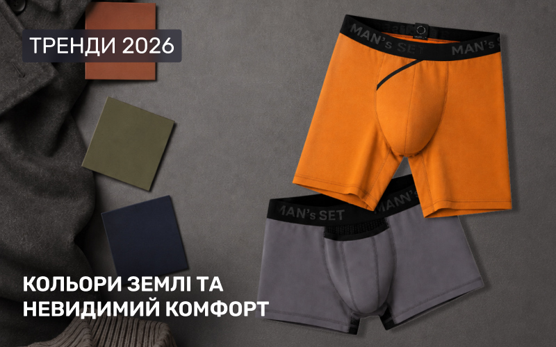 Тренди чоловічої білизни 2026 року в концепції "Кольори землі та невидимий комфорт" від Man's Set: яскраві помаранчеві та практичні темно-сірі анатомічні боксери лежать на темному текстурованому тлі поруч із краєм вовняного пальта та трьома квадратними зразками кольорів (теракотовий, оливковий, темно-синій).