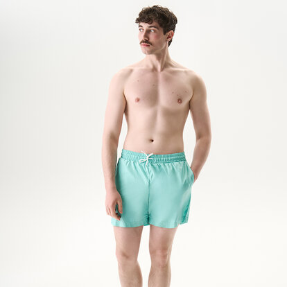 Мужчина в шортах для плавания Anatomic Shorts 2.0, бирюзовый во время отдыха